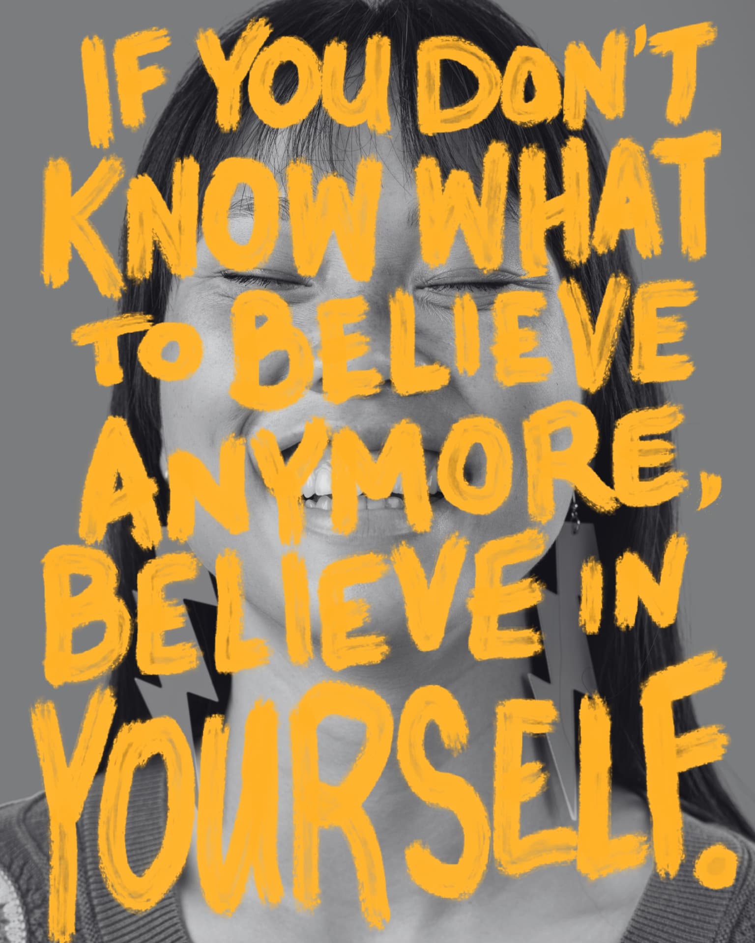 Greyscale portrait of a laughing woman overlaid with bold orange hand-painted letters reading If you don't know what to believe anymore, believe in yourself.