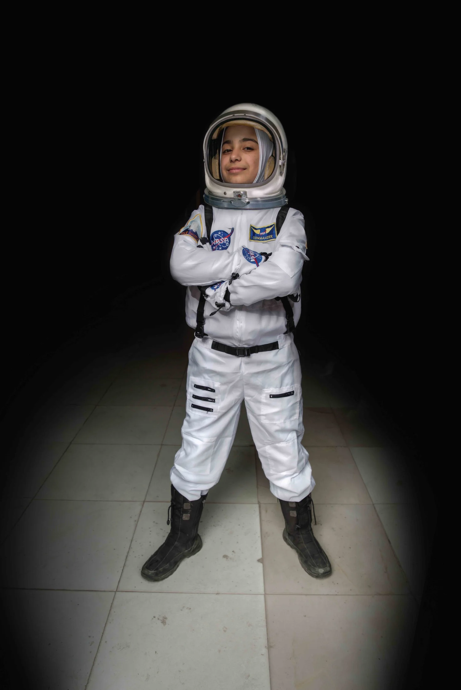 Child in a full white astronaut suit standing in a pool of light